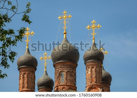 Black domes with golden crosses of the old orthodox church against the blue sky