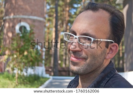 Beautiful portrait of a brutal man, guy, brunette, with stubble and glasses, on a minimalistic background