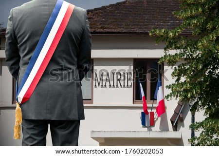 A town hall and the French flag with the mayor in front. Royalty-Free Stock Photo #1760202053