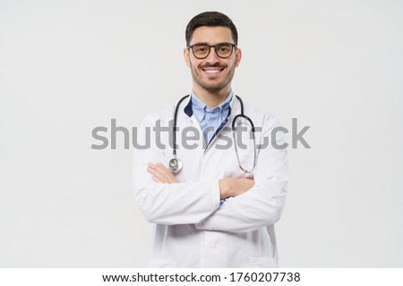 Portrait of smiling young male doctor with stethoscope around neck standing with crossed arms in white coat, isolated on gray background  Royalty-Free Stock Photo #1760207738