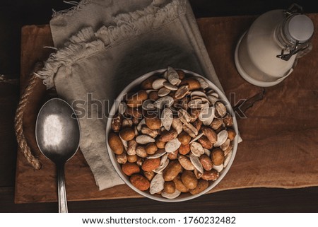mix of peanuts and seeds in a bowl on a cloth napkin and milk