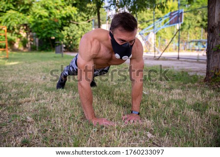 Muscular young fitness athlete in training mask, doing push-ups
