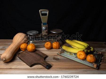 oranges, bananas, a pumpkin and old accessories on wood