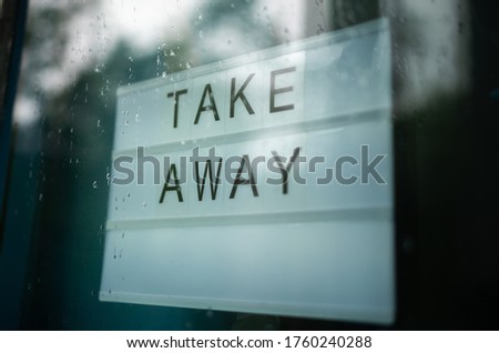 Lightbox with as sign Take Away behind a glass door of the cafe.