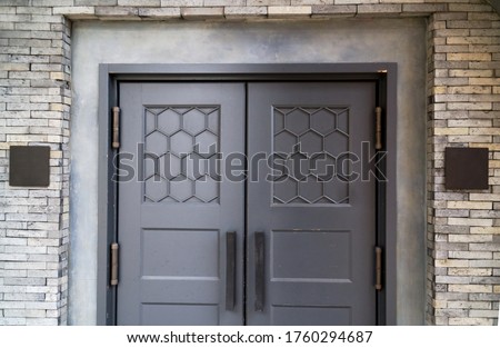 Abstract shop entrance in modern mix vintage European design grey wooden door and stone work wall and gray blank name plate. Taken in soft spot focus.