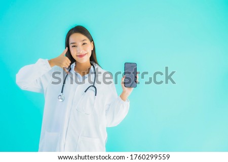 Portrait beautiful young asian doctor woman use mobile smart cell phone for clinic or hospital on blue isolated background