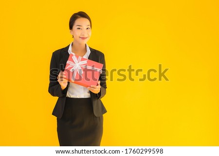 Portrait beautiful young asian woman show red gift box with happy smile on yellow isolated background