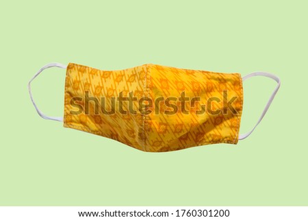 Yellow flower pattern cloth mask, Hygienic cotton mask ,fabric face breathing mask for protect pm2.5 and corona virus (covid-19) on soft yellow background with clipping path.
