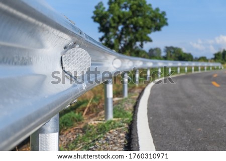 White reflective sign warn curve at night on the steel guard rail on the road or street in the countryside with blue sky in day time close-up. Royalty-Free Stock Photo #1760310971