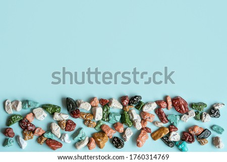 Colorful pebbles stones for decoration and for hand made works. Сolorful stone, texture on the blue background. Concept we are all different.