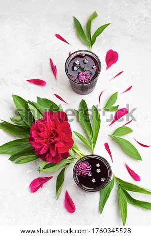 Hibiscus or red sorrel, Agua de flor de Jamaica tea in two glasses with magenta peony and peonies petal. Top view. Grey background.