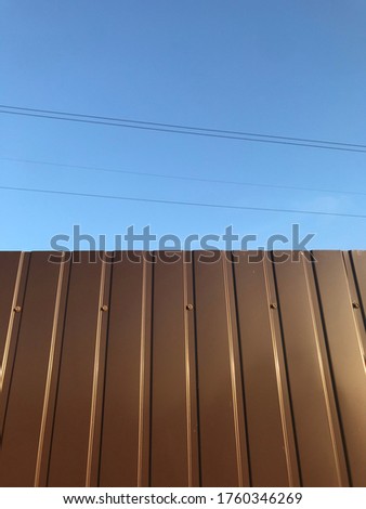 brown sheet metal fence against blue sky