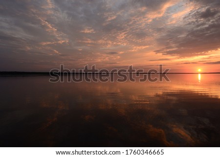 Bright colors of the sky at sunset in the silence of a summer evening reflected on the lake water