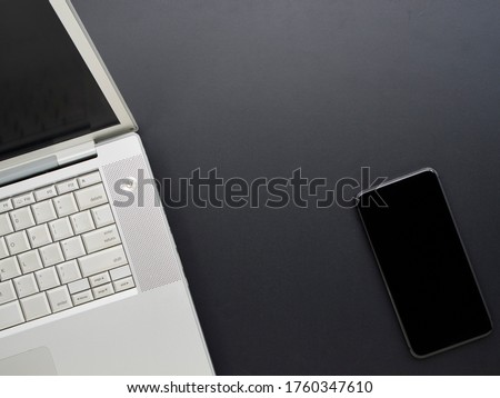 Home office workspace mockup with laptop and smartphone on black background. Top view, space for text.