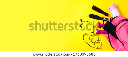 Pink sports bag and accessories on yellow background