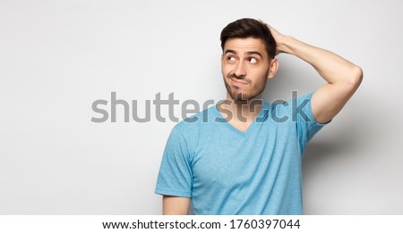 Young doubtful man thinking, scratching head and trying to find solution, isolated on gray background Royalty-Free Stock Photo #1760397044