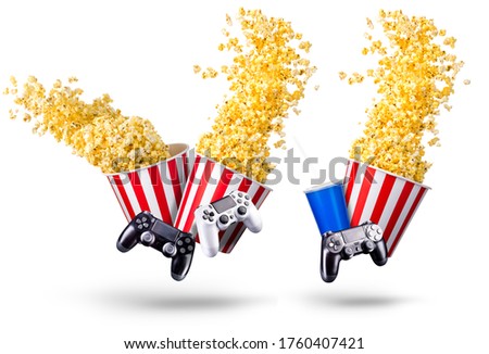 Paper striped bucket with popcorn, cup of soft drink and video game joystick isolated on white background, movie night concept or watching TV.