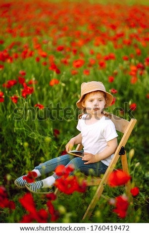 Cute little child girl in poppy field. Adorable child playing on sunny field.