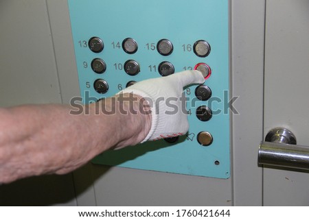 A man in white gloves presses the floor button in the Elevator