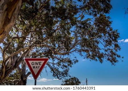 Closeup of a tree and a traffic sign in the foreground in an agriculture landscape in the Grampians national park in Victoria, Australia at a cloudy day in summer.