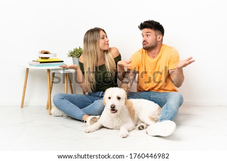 Young caucasian couple with dog staying at home having doubts Royalty-Free Stock Photo #1760446982