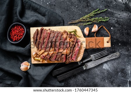 Grilled rib eye, ribeye steak on a chopping Board, medium rare. marbled meat. black background. top view