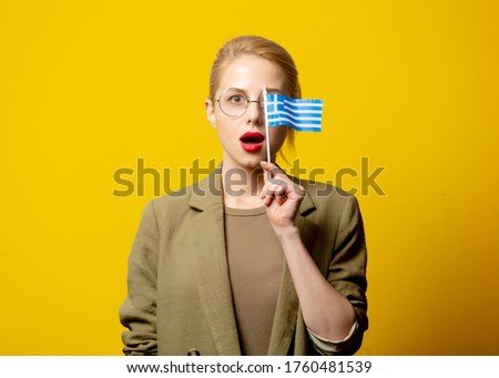 Style blonde woman in jacket with Greek flag on yellow background