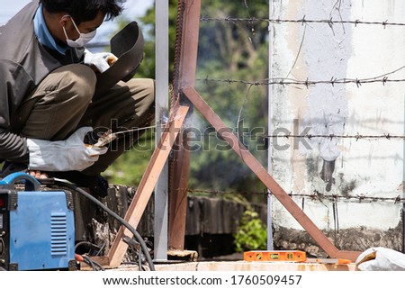 The workers welding steel (made pole)
