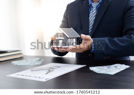 Sales manager or real estate agent prepares to hand over the keys and the house together with the insurance to the customer, Attention to property services and insurance concept.