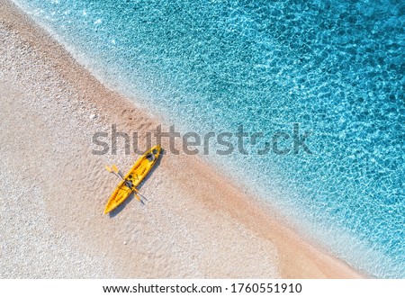 Aerial view of empty sandy beach with yellow canoe, sea coast with transparent blue water in sunny bright day in summer. Travel in Croatia. Top view of boat. Landscape with kayak at sunset. Travel Royalty-Free Stock Photo #1760551910