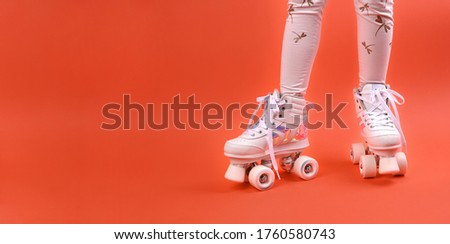 Roller skates on the legs of a urenburg. Retro rollers on a bright background. The concept of children's outdoor sports. Free space for text. Long format.