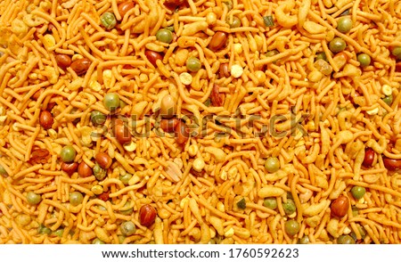 Backdrop made of Indian mix snack, deep fried salty dish - chivda made of flour, mixed with roasted nuts, pepper, pulses, spice and green peas. Bombay mix background Royalty-Free Stock Photo #1760592623