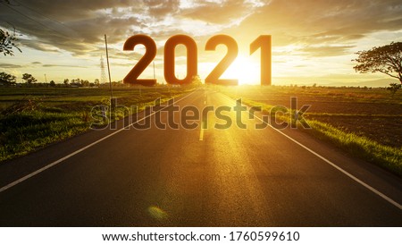 The word 2021 behind the tree of empty asphalt road at golden sunset and beautiful blue sky. Concept for vision year 2021.  Royalty-Free Stock Photo #1760599610