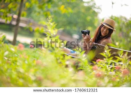 attrative girl with mini camera in her hand smile on camera in the beautiful garden