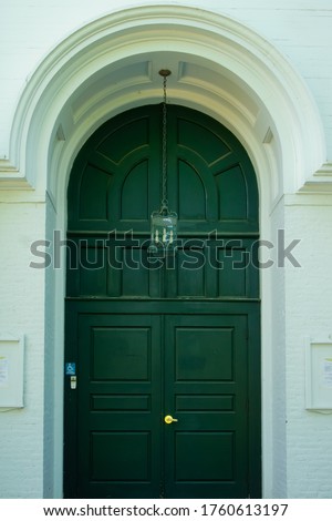 Sherborn, Massachusetts /United States-arched doorway with dark green wood door and hanging lamp of historic pilgrim church