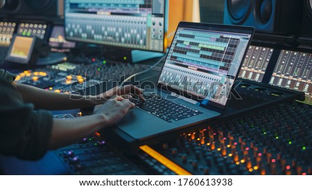 Modern Music Record Studio Control Desk with Laptop Screen Showing User Interface of Digital Audio Workstation Software. Equalizer, Mixer and Professional Equipment. Faders, Sliders. Record. Close-up Royalty-Free Stock Photo #1760613938