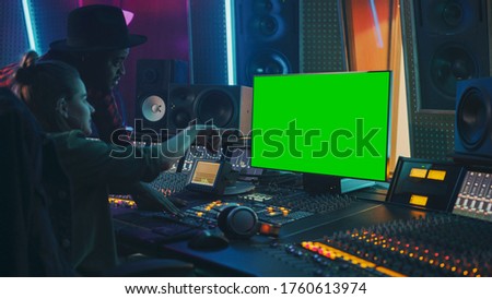 Producer and Audio Engineer Working together in Music Record Studio on a New Album, Use Green Screen Computer, Control Desk for Mixing and Creating Hit Song. Artist and Musician Collaboration