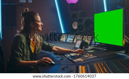 Portrait of Stylish Female Audio Engineer / Producer Working in Music Record Studio, Uses Green Screen Computer Display, Mixer Board, Control Desk to Create New Song. Creative Artist Musician