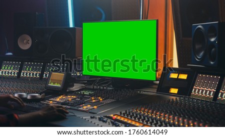 Portrait of Stylish Audio Engineer Working in Music Record Studio, Uses Green Screen Computer, Mixer Board, Control Desk to Create New Song. Over the Shoulder Shot