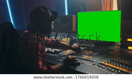 Portrait of Stylish Audio Engineer / Producer Working in Music Record Studio, Uses Green Screen Computer, Mixer Board, Control Desk to Create New Song. Creative Black Artist Musician