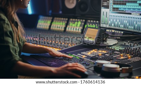 Beautiful, Stylish Female Audio Engineer, Producer Working in Music Recording Studio, Uses Mixing Board, Software to Create Cool Song. Creative Girl Artist Musician Working. Royalty-Free Stock Photo #1760614136
