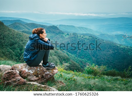 Sad depressed woman adult sitting on mountain rock worried anxious thinking of problems on mountain view in nature Royalty-Free Stock Photo #1760625326