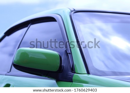 close up of green car wing mirror and windows