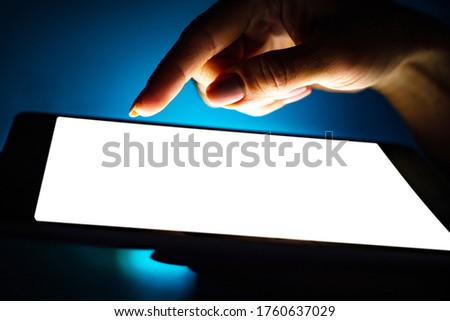 Close up view of girl using tablet with white screen on dark background