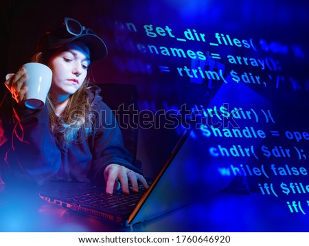 A girl at a laptop against the background of computer code. Software development. Computer languages. The programmer works remotely. Freelance.