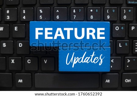 Top view of computer keyboard and blue wooden cube written with Feature Updates. Royalty-Free Stock Photo #1760652392