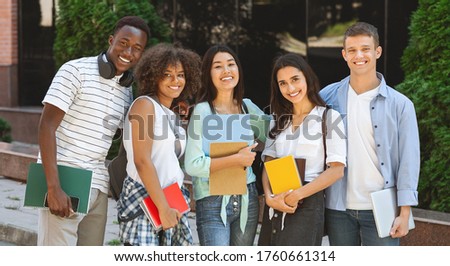 Portrait of happy international students posing outdoors near university building, smiling and embracing, taking group photo, panorama
