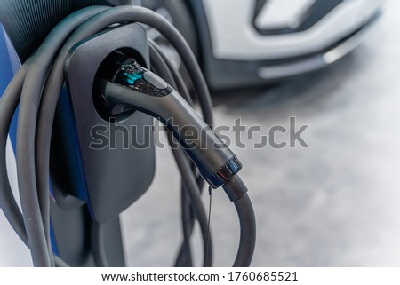 close up view of electric car charger with blurred car background,selective focus.