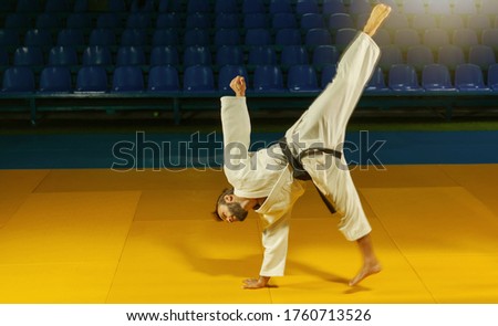 Sport man in white kimono practices capoeira in the sports hall