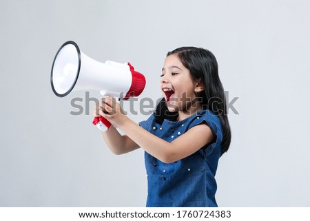 Indian Girl Kid with megaphone shouting on white banner background with copy space Royalty-Free Stock Photo #1760724383